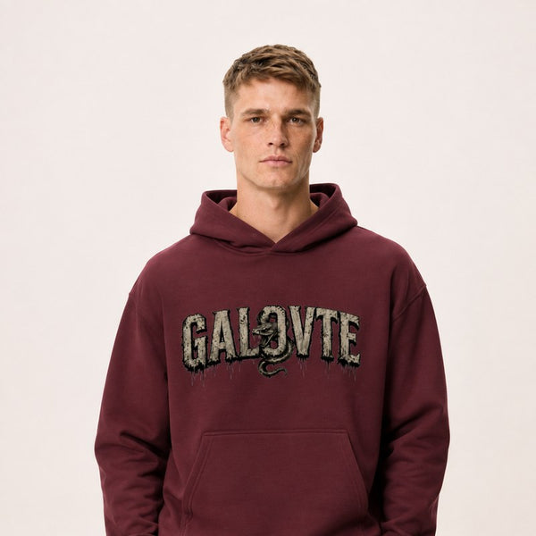 A model wearing a maroon GALOVTE varsity graphic heavyweight hoodie.