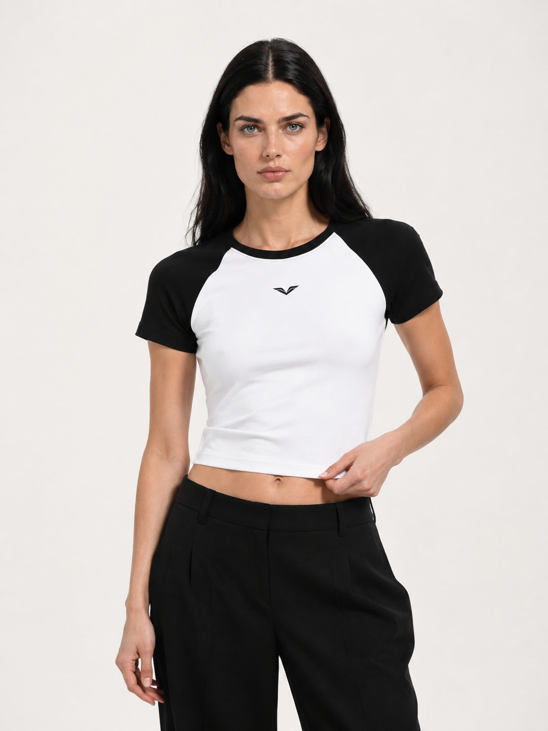 Model wearing white raglan baby tee with black sleeves, carrying the GALOVTE winged chevron logo.
