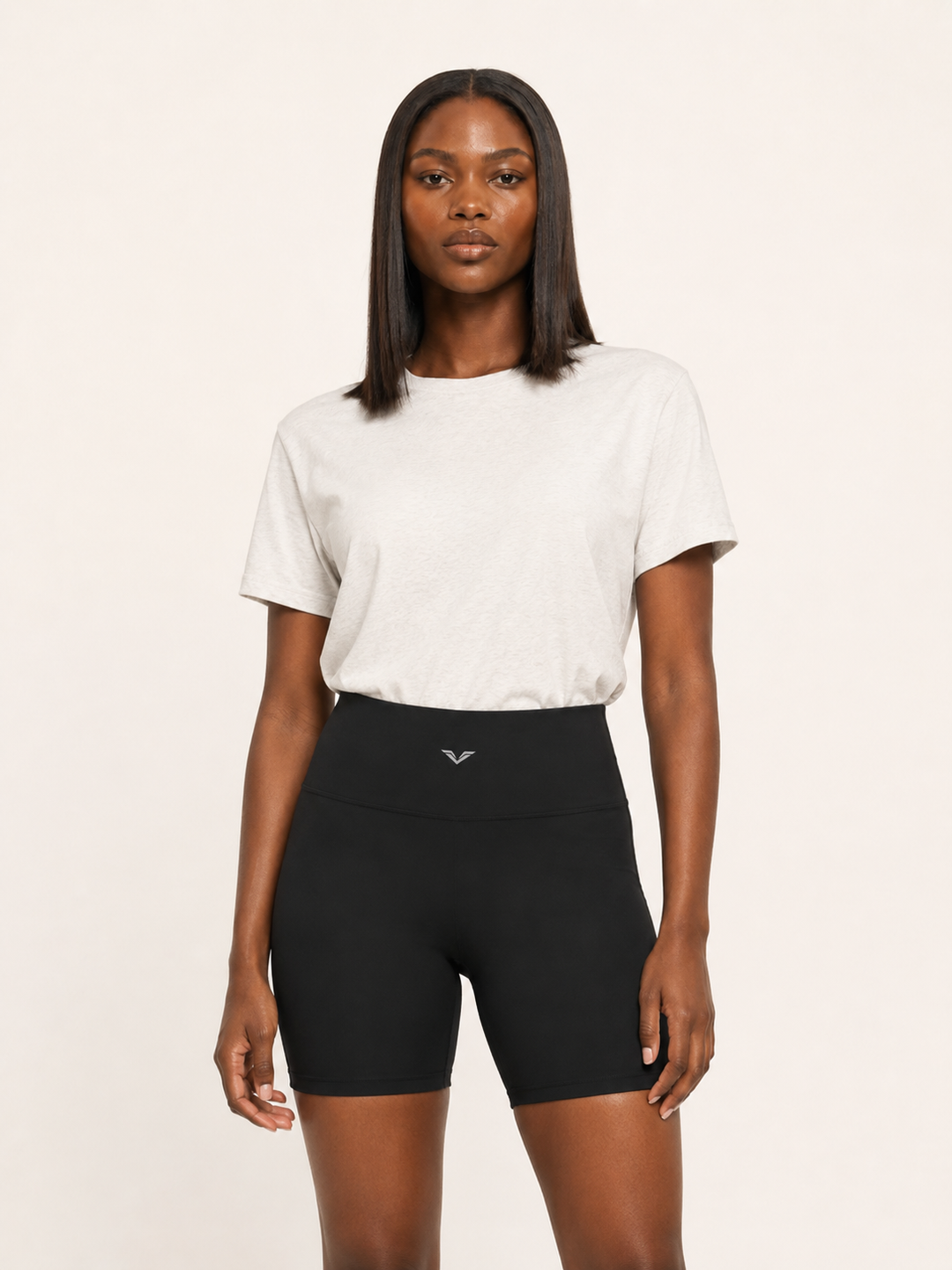 Model wearing black high-waisted biker shorts, carrying the GALOVTE winged chevron logo.