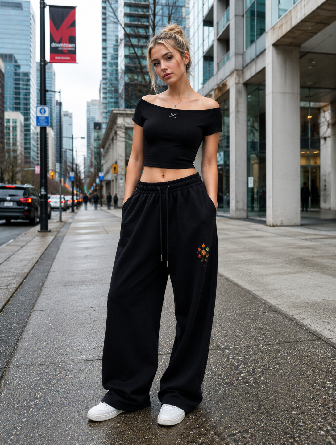Wing Logo Wide-Neck Baby Tee in Black, worn with black sweatpants on a city street.