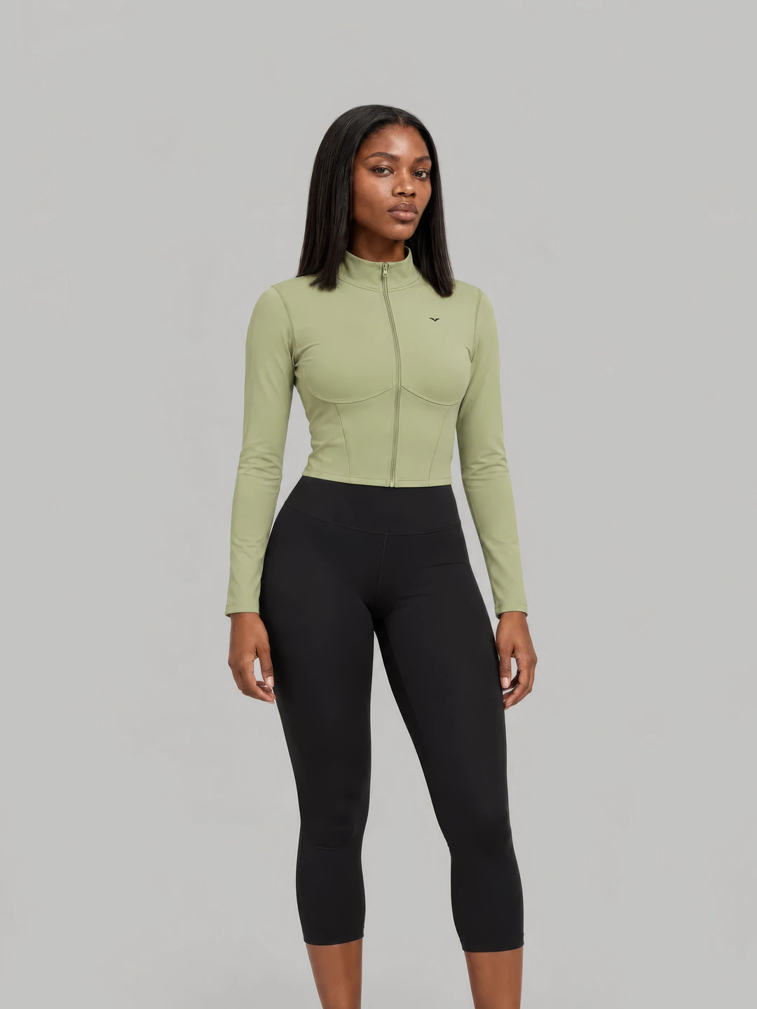 Model in a sage GALOVTE cropped full-zip jacket and black leggings
