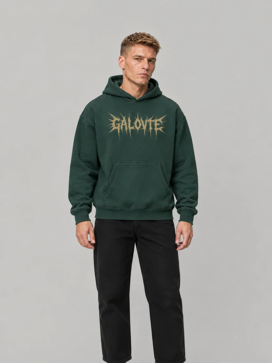 Model in a dark green GALOVTE spiked-logo oversized hoodie