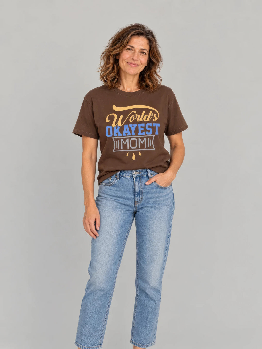 Mother in a brown World's Okayest Mom tee and light-blue jeans