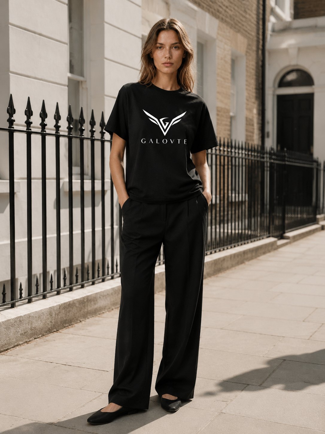 Model in a black GALOVTE logo t-shirt and wide-leg trousers on a London street